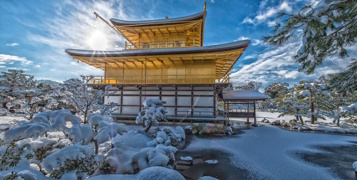 Goldener Pavillion und Tempel in Kioto im Schnee vor blauem Himmel Winterlandschaft