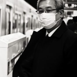 Mann mit weißer Mund-Maske in Japan in U-Bahnhof