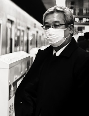 Mann mit weißer Mund-Maske in Japan in U-Bahnhof